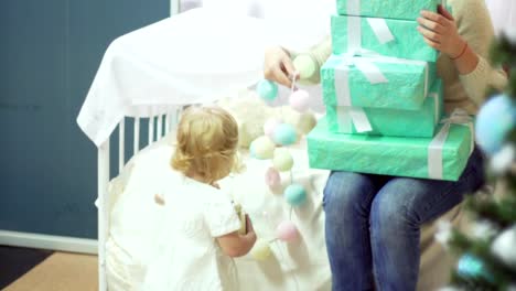 Glückliche-junge-Mutter-mit-ihrem-süßen-Baby-halten-verziert-Boxen-mit-Geschenken