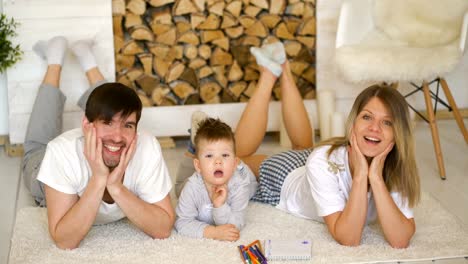 Retrato-de-una-familia-encantadora-posando-y-sonriendo-en-el-suelo-en-su-sala-de-estar