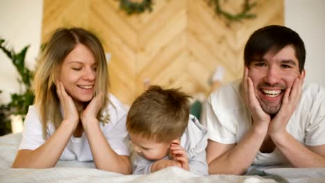 Portrait-of-a-lovely-family-posing-and-smiling-on-bed-in-their-bedroom