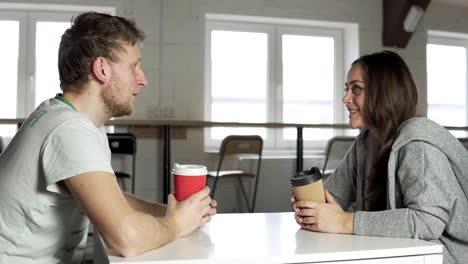 Dos-amigos-están-sentados-en-la-mesa-de-café,-beber-café-para-llevar-en-vasos-de-papel-y-hablar.-Rodada-en-4k