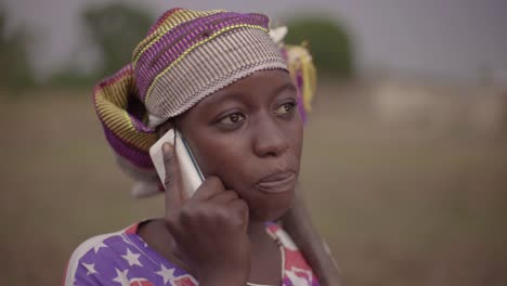 Portrait-of-a-young-African-female-farmer-spontaneously-talking-on-her-cellphone