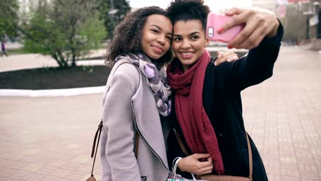 Zwei-niedliche-afroamerikanische-Frau-nehmen-Selfie-mit-Einkaufstüten-und-lächelnd.-Freunden-haben-Spaß-nach-dem-Besuch-der-Mall-Verkauf.