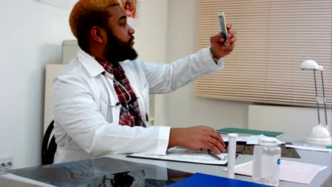 Doctor-masculino-americano-africano-tomando-selfie-y-mostrando-pulgar