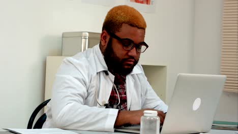 African-american-male-doctor-working-on-laptop-at-his-desk