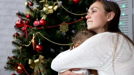 Niedliche-kleine-Mädchen-Spaß-und-küssen-ihre-Mutter-neben-Weihnachtsbaum