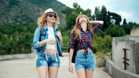 Two-pretty-young-women-friends-travelers-walk-outdoors-on-mountain-scene