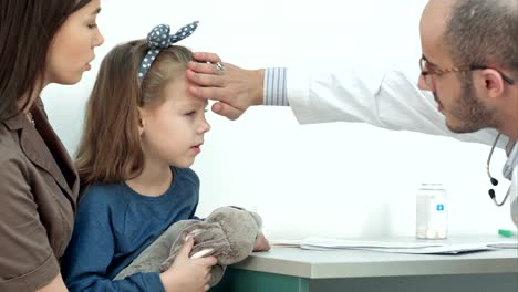 Male-pediatrician-checking-little-girl-head-for-fever