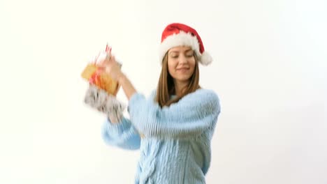 Cute-blonde-in-santa's-hat-dancing-with-festive-gifts-at-a-white-background