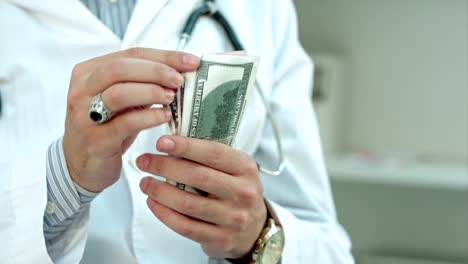 Male-doctor-counting-money-and-putting-it-in-his-pocket