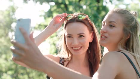 Two-beautiful-teenage-girls-using-phone-in-a-city-park.