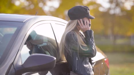 Schöne-junge-Blonde-telefonieren-mit-dem-Auto