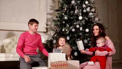 family-give-each-other-presents-during-the-New-Year-,-they-are-sitting-near-the-Christmas-tree