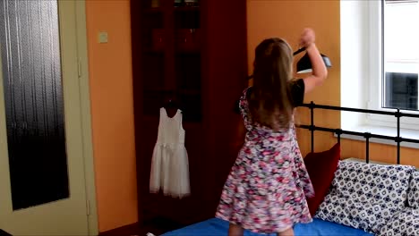 Cute-little-girl-dances-on-a-bed.-Childhood-concept