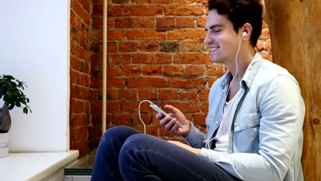 Man-Listening-Music-on-Smartphone-and-Dancing,-Sitting-on-Stairs