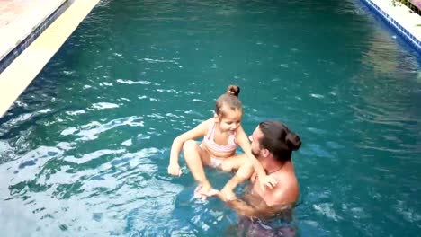 Happy-family,-active-father-with-little-child,-adorable-toddler-daughter,-having-fun-in-swimming-pool.