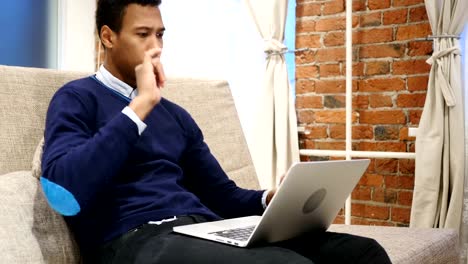 African-Man-Enjoying-Listening-Music-on-Laptop,-Relaxing-at-Home