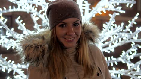 Young-Woman-In-Warm-Clothing-Smiling,-Standing-Amid-Christmas-Illuminations