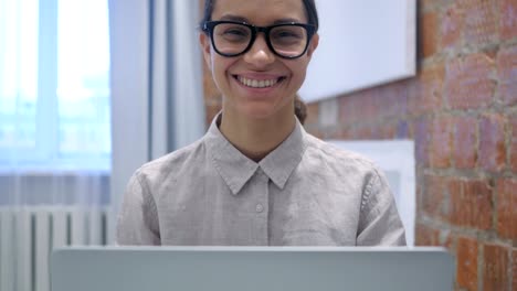 Lächelnde-Hispanic-Frau-sitzen-und-arbeiten-am-Laptop