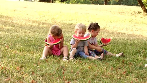 Group-of-children-eating-watermelon-outdoors.4K