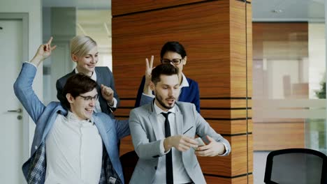 Happy-business-team-taking-selfie-portrait-on-smartphone-camera-and-posing-for-group-photo-during-meeting-in-modern-office
