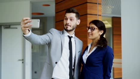 Feliz-hombre-de-negocios-y-su-colega-tomando-un-selfie-en-Smartphone-cámara-para-comunicación-social-en-oficina-moderna