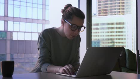 Geschäftsfrau-in-Hipster-Gläser-startet-am-Laptop-arbeiten.-Weiblich-ist-Computer-im-Büro-verwenden,-lächelnd-und-Schreiben-auf-einer-Tastatur