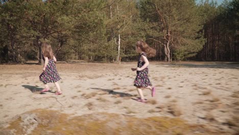 two-girls-are-running-on-sand-in-a-summer-forest