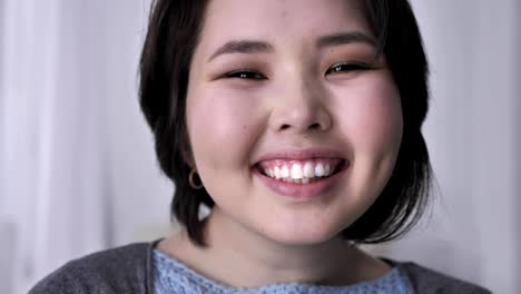 Portrait-of-a-young-asian-brunette-girl-looking-into-the-camera,-surprised,-joyfully-smiling,-looking.-50-fps