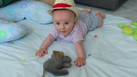 Lindo-bebé-de-5-meses-de-edad-con-su-sombrero-de-paja-sobre-una-estera-de-juego