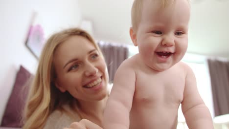 Nacktes-Baby-mit-fünf-Zähne-Lächeln.-Happy-baby-mit-Mutter-Lächeln-und-Spaß-haben