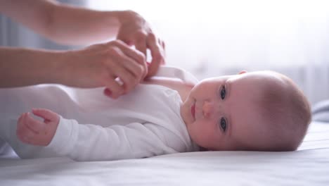 Mother-carefully-dressing-her-baby