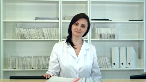 Female-nurse-at-hospital-reception-looking-at-camera