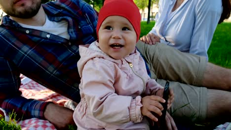 Little-baby-girl-holding-smartphone-in-hands-and-laughing-close-up-on-nature-in-summer