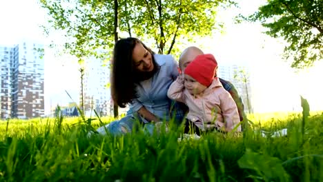 Familia-feliz-está-descansando-en-la-naturaleza.-Los-padres-juegan-con-una-hija-pequeña-en-un-parque-en-el-verano-en-puesta-de-sol,-movimiento-de-la-cámara