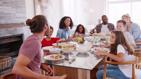 Retrato-de-dos-familias-disfrutando-de-comida-en-casa-juntos