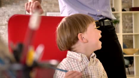 Father-circling-around-his-little-son-on-chair,-happy-kid-cheering-and-sitting-in-modern-office