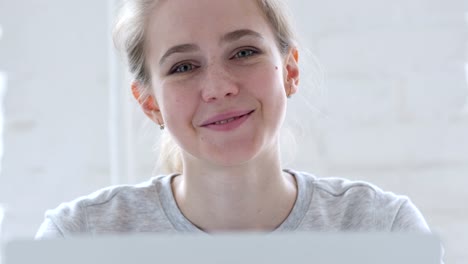 Junge-Frau-lächelnd-als-Blick-in-die-Kamera-bei-der-Arbeit