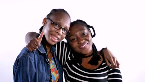 Two-young-african-american-women-hugging-and-smiling-at-camera,-happy,-isolated-over-white-background,-black-friends-laughing