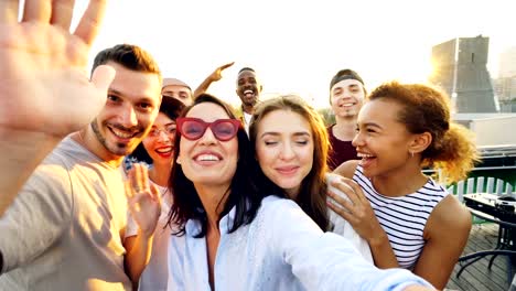 Point-of-view-shot-of-young-people-making-video-call,-looking-at-camera,-talking-and-laughing-during-party-on-rooftop.-Modern-technology-and-communication-concept.