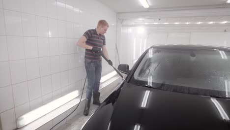 Faceless-person-watering-wheel-in-car-wash