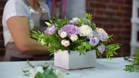 professional-florist-arranging-beatiful-flower-composition-in-wooden-box-in-floral-design-studio