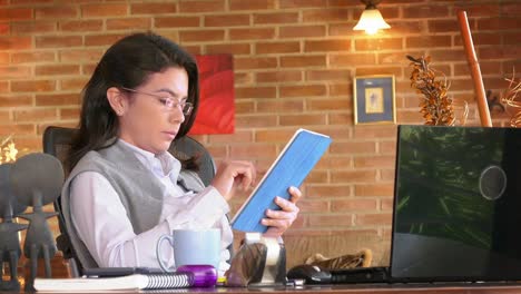 Home-Office.-Dolly-shot-of-a-freelance-Hispanic-young-woman-using-digital-tablet-and-drinking-coffee.