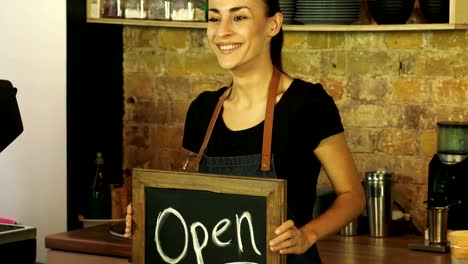 A-coffee-shop-worker-holds-a-Open-sign.