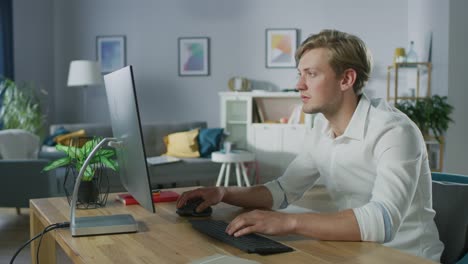 Handsome-Young-Designer-Works-On-Personal-Computer-Sitting-at-His-Desk.-In-the-Background-Stylish-Home-Decor.