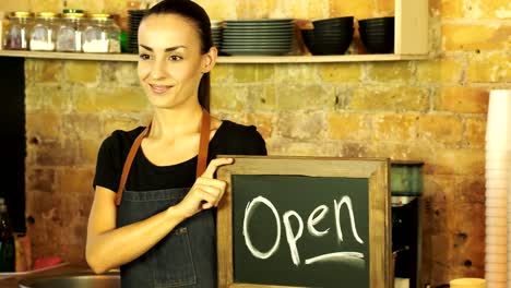 A-coffee-shop-worker-holds-a-Open-sign.