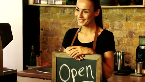 A-coffee-shop-worker-holds-a-Open-sign.