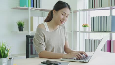 Attractive-young-asian-woman-smiling-positive-at-home-office.