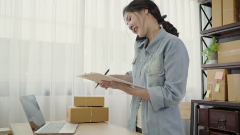 Smart-asiático-mujer-empresario-de-PYME-en-línea-mediante-llamada-telefónica-reciben-de-producto-control-de-cliente-en-la-acción-y-escribir-en-el-portapapeles-trabajo-en-casa.-Pequeño-empresario-en-concepto-de-la-oficina-en-casa.