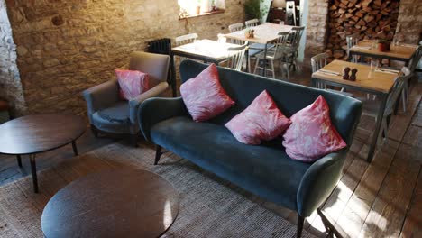 Empty-lounge,-dining-space-and-bar-in-a-gastro-pub-in-daylight,-with-feature-stone-walls-and-old-wooden-floorboards,-handheld,-elevated-view