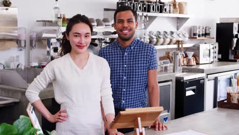 Young-mixed-race-couple-coffee-shop-owners-looking-to-camera